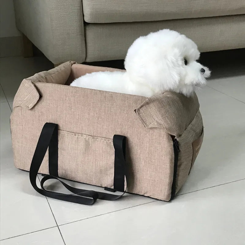 Small white dog in a beige pet carrier bag on tiled floor, Carcader home setting