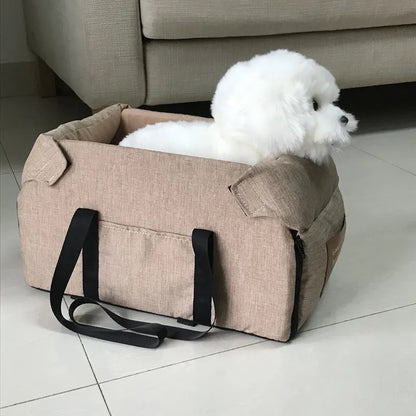 Small white dog in a beige pet carrier bag on tiled floor, Carcader home setting