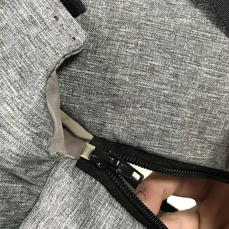 Close-up of gray fabric Carcader bag with black zipper partially open.